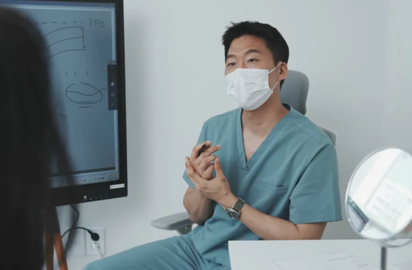 A doctor at a Jamsil dermatology clinic sitting across from a patient, explaining their skin condition